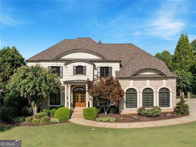 french country inspired facade featuring a front lawn