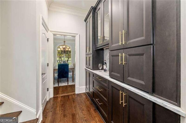 interior space featuring dark hardwood / wood-style floors, an inviting chandelier, dark brown cabinetry, and ornamental molding