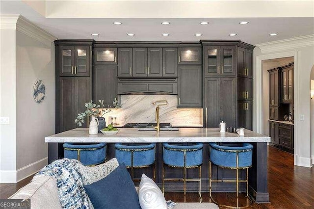 kitchen with an island with sink, crown molding, and custom exhaust hood