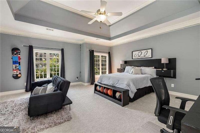 carpeted bedroom with crown molding, ceiling fan, and a tray ceiling