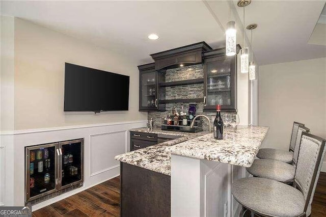 bar featuring pendant lighting, dark hardwood / wood-style floors, and light stone countertops