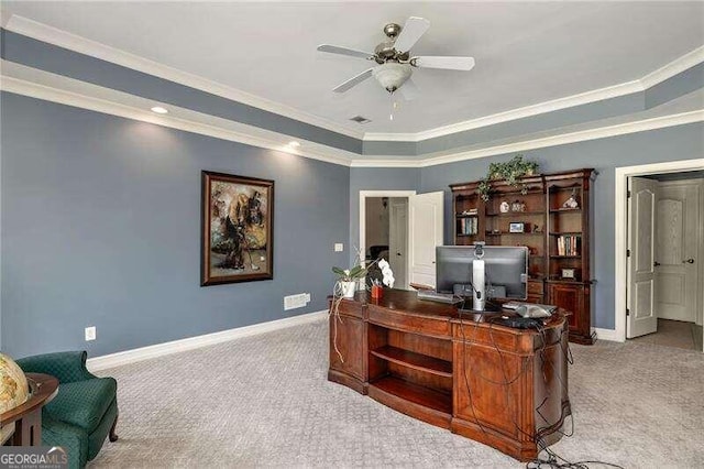 carpeted office with a tray ceiling, ceiling fan, and ornamental molding