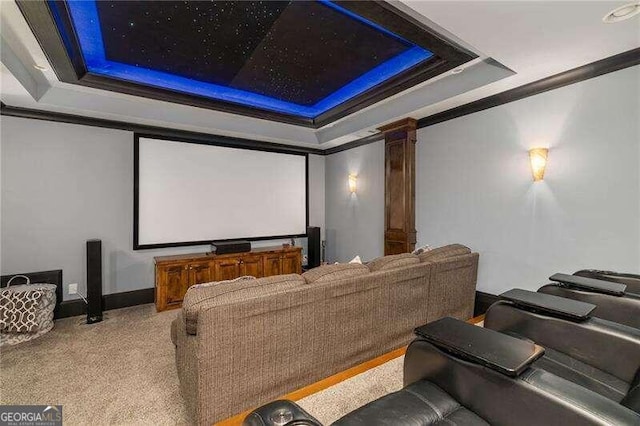 carpeted cinema with a tray ceiling, decorative columns, and ornamental molding