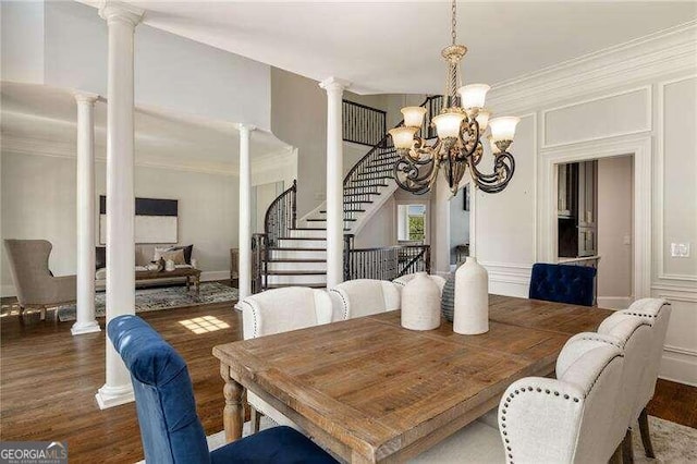 dining room with dark wood-type flooring, ornamental molding, a chandelier, and ornate columns