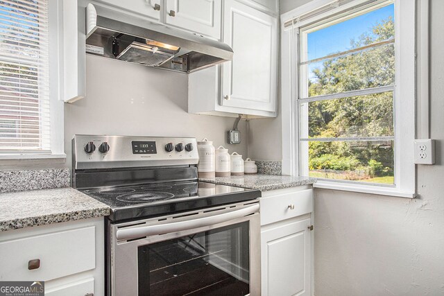 kitchen with light stone countertops, a healthy amount of sunlight, white cabinets, and stainless steel electric stove