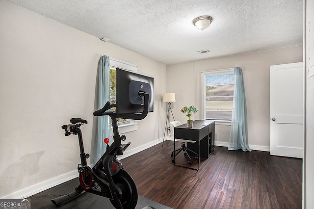 exercise room featuring dark wood-type flooring and a textured ceiling