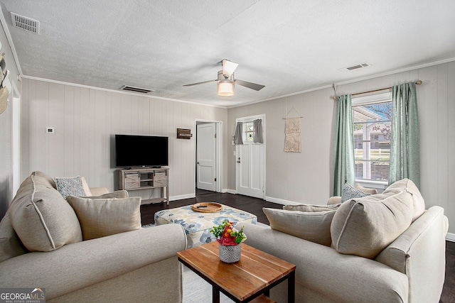 living room with dark hardwood / wood-style floors, crown molding, wooden walls, and ceiling fan