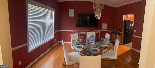 dining space with ornamental molding, a chandelier, and light hardwood / wood-style floors