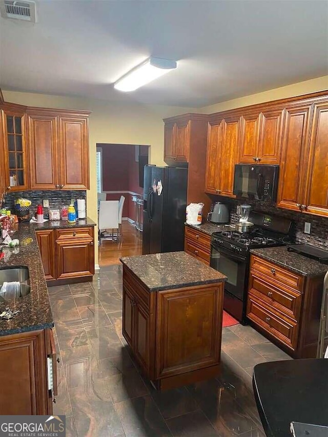 kitchen with black appliances, tasteful backsplash, a center island, and dark stone counters