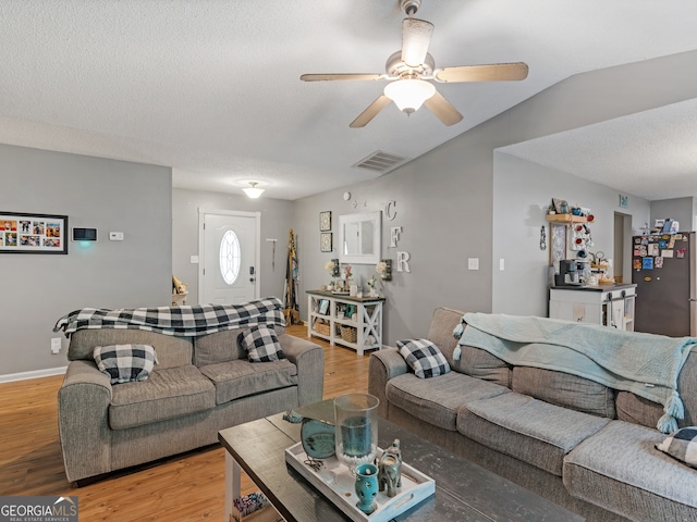 living room featuring lofted ceiling, hardwood / wood-style flooring, ceiling fan, and a textured ceiling