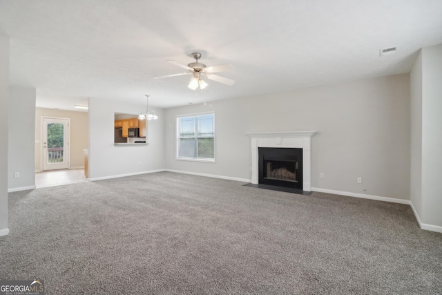 unfurnished living room with a healthy amount of sunlight, a fireplace with flush hearth, visible vents, and carpet flooring