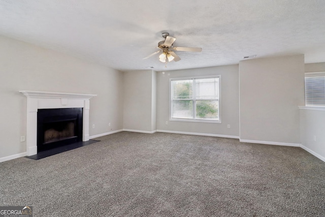 unfurnished living room featuring ceiling fan, carpet floors, a fireplace with flush hearth, visible vents, and baseboards