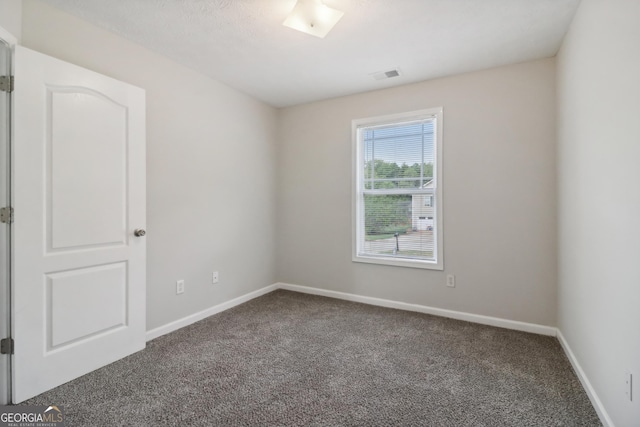 spare room featuring carpet flooring, visible vents, and baseboards