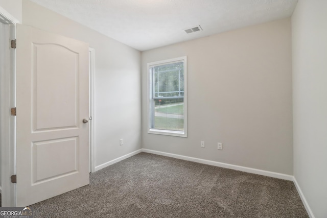 carpeted spare room featuring visible vents and baseboards