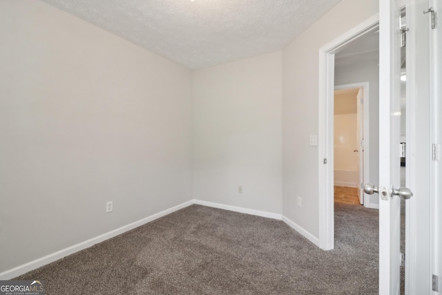 empty room featuring carpet floors, baseboards, and a textured ceiling