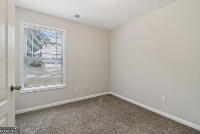 carpeted spare room with visible vents and baseboards