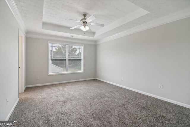 carpeted empty room with ceiling fan, a raised ceiling, and ornamental molding