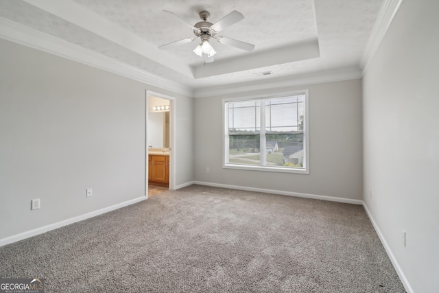 unfurnished bedroom with a tray ceiling, light colored carpet, crown molding, and baseboards