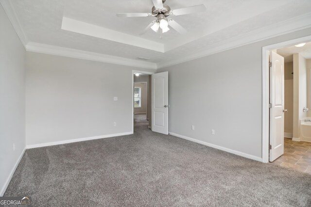 spare room featuring carpet, ceiling fan, ornamental molding, and a tray ceiling