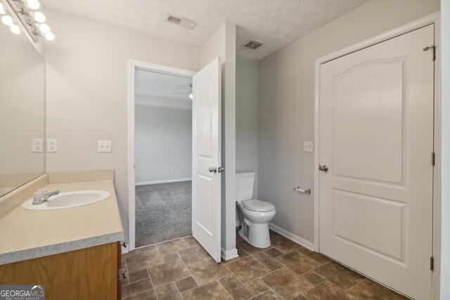 bathroom featuring visible vents, vanity, toilet, and a textured ceiling