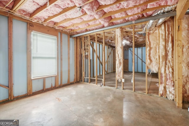 misc room with electric panel and unfinished concrete flooring