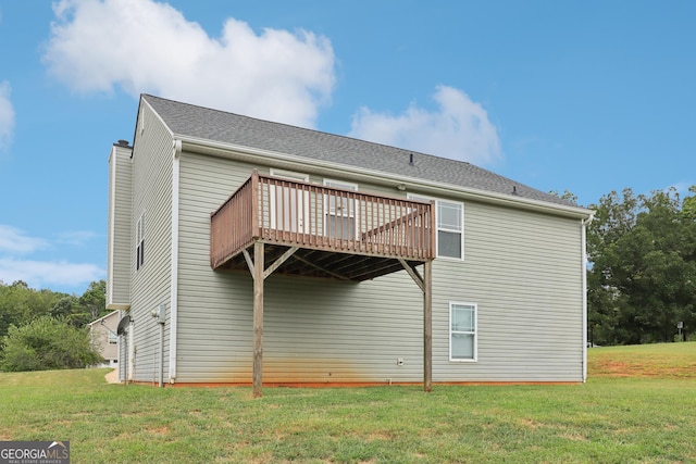 rear view of property with a shingled roof, a chimney, a lawn, and a deck