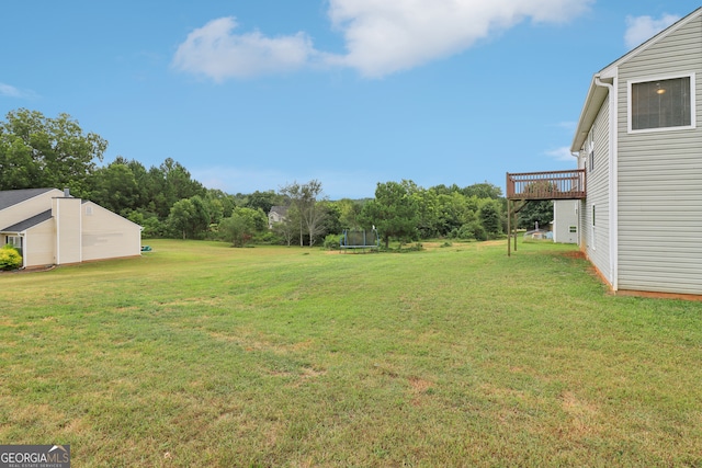 view of yard with a deck and a trampoline