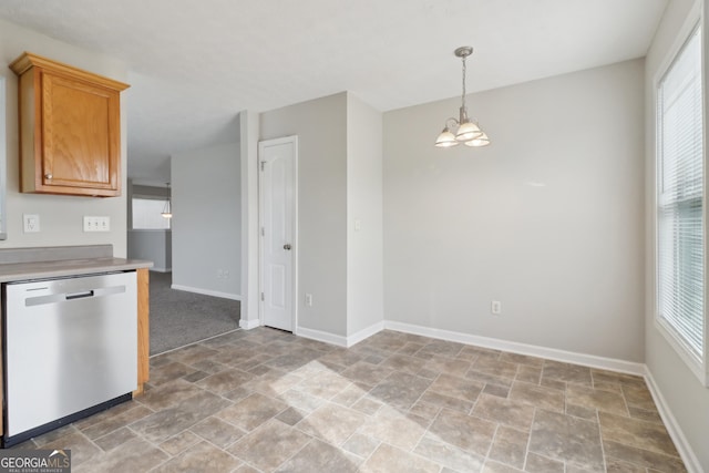 kitchen with a notable chandelier, light countertops, stainless steel dishwasher, stone finish flooring, and baseboards