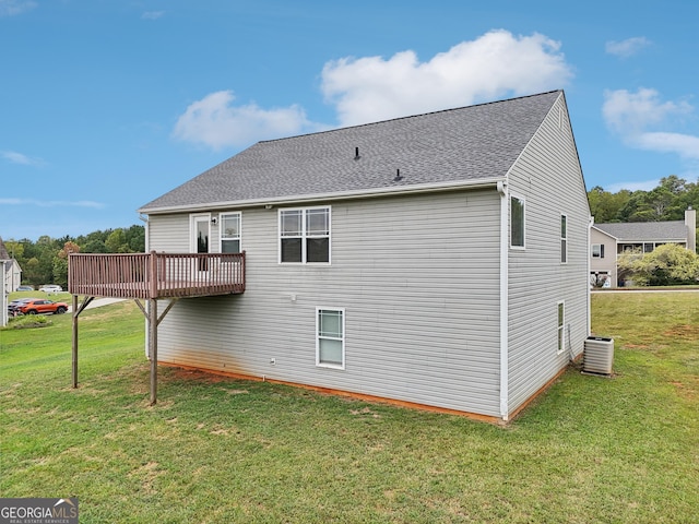 back of property with a shingled roof, a lawn, a wooden deck, and central AC unit