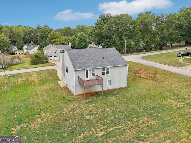 rear view of house featuring roof with shingles and a yard