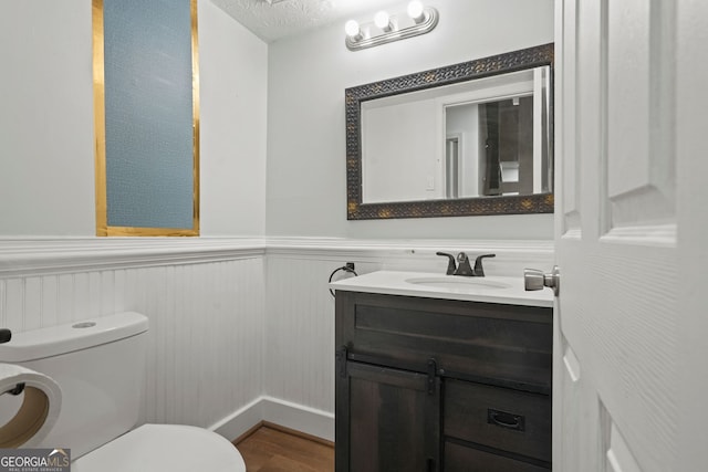 bathroom with a textured ceiling, vanity, toilet, and wood-type flooring