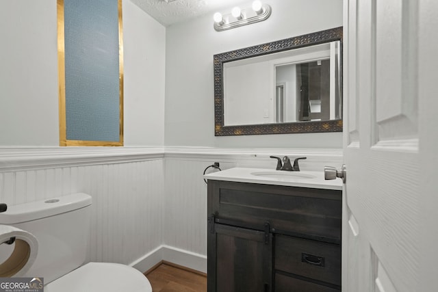 6584 Sleepy Hollow Ln, Morrow, GA 30260 - half bathroom with toilet, wainscoting, vanity, wood finished floors, and a textured ceiling