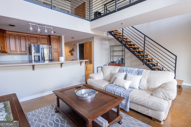 living room featuring a towering ceiling and concrete flooring