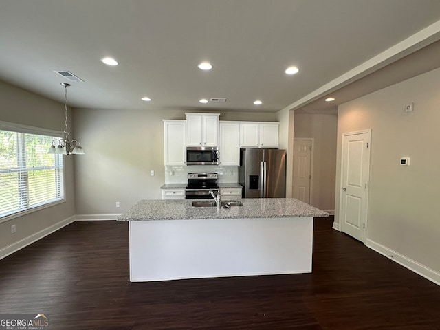 kitchen featuring appliances with stainless steel finishes, a center island with sink, light stone countertops, and dark hardwood / wood-style floors