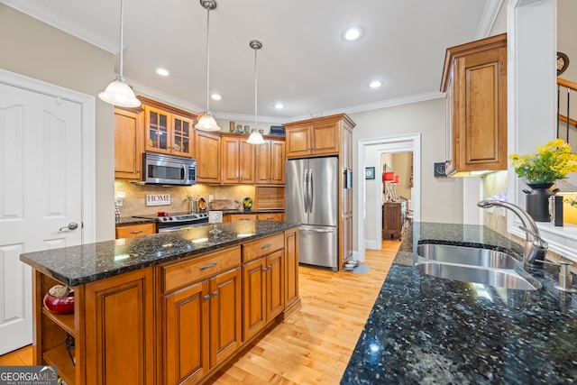 kitchen featuring dark stone countertops, a kitchen island, sink, appliances with stainless steel finishes, and light hardwood / wood-style floors