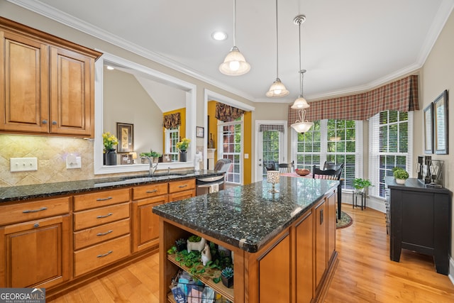 kitchen featuring light wood-type flooring, a center island, sink, and hanging light fixtures