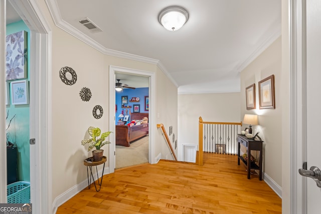 hall with ornamental molding and light hardwood / wood-style flooring