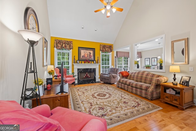 living room with high vaulted ceiling, ceiling fan, a fireplace, and light wood-type flooring