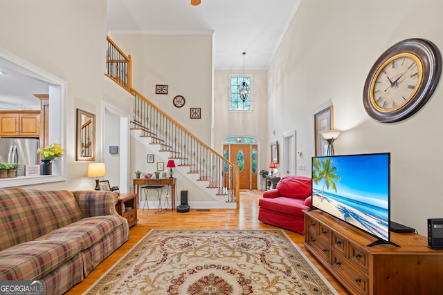 living room featuring a high ceiling, ornamental molding, and light hardwood / wood-style flooring