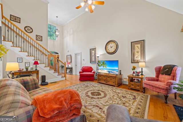 living room with high vaulted ceiling, hardwood / wood-style floors, ceiling fan with notable chandelier, and crown molding