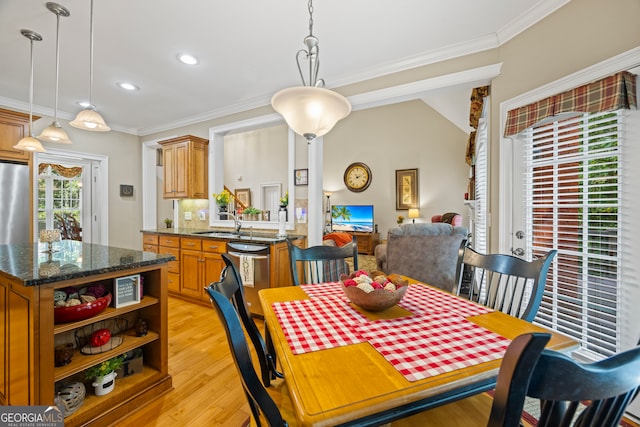 dining room featuring ornamental molding, lofted ceiling, sink, and light hardwood / wood-style floors