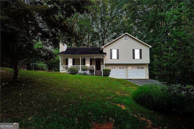 tri-level home featuring covered porch, a front yard, and a garage