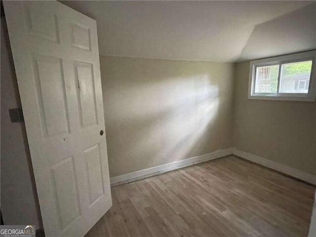 additional living space with vaulted ceiling and hardwood / wood-style flooring