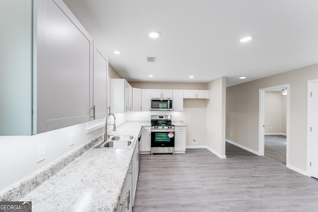 kitchen with white cabinetry, light hardwood / wood-style flooring, stainless steel appliances, sink, and ceiling fan