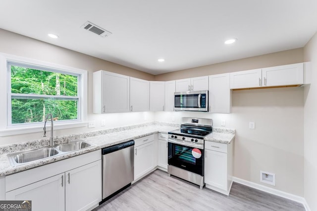 kitchen featuring appliances with stainless steel finishes, light hardwood / wood-style flooring, sink, and white cabinets