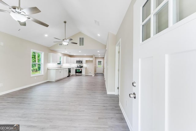 unfurnished living room featuring high vaulted ceiling, ceiling fan, and light hardwood / wood-style floors