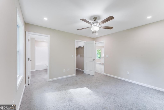 unfurnished bedroom featuring ceiling fan, a walk in closet, a closet, and ensuite bathroom