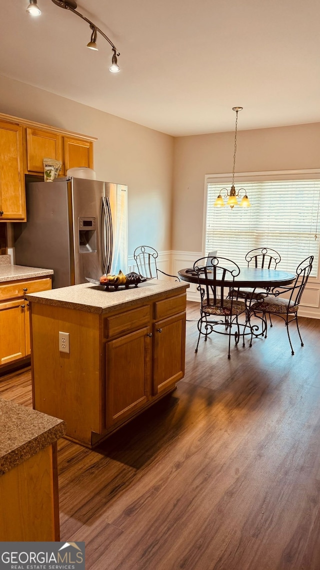 kitchen with stainless steel fridge, a kitchen island, decorative light fixtures, and dark hardwood / wood-style floors