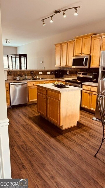 kitchen featuring appliances with stainless steel finishes, sink, dark hardwood / wood-style floors, kitchen peninsula, and a kitchen island