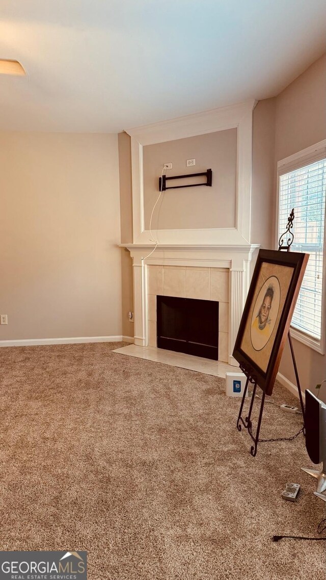 unfurnished room featuring carpet floors and a tile fireplace